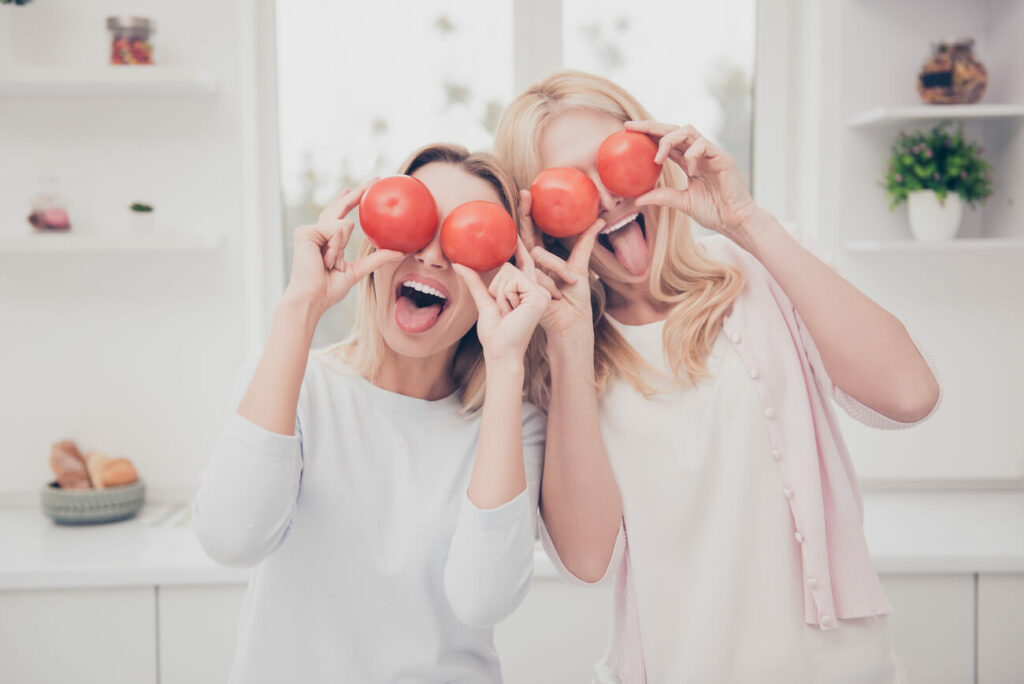 2 vegane Frauen machen Quatsch mit Tomaten vor den Augen